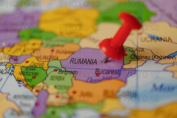 Romania marked with a red thumbtack on a map with an out-of-focus background