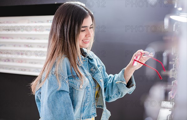 Customer choosing glasses in an eyewear store. Beautiful girl choosing glasses in an optical store