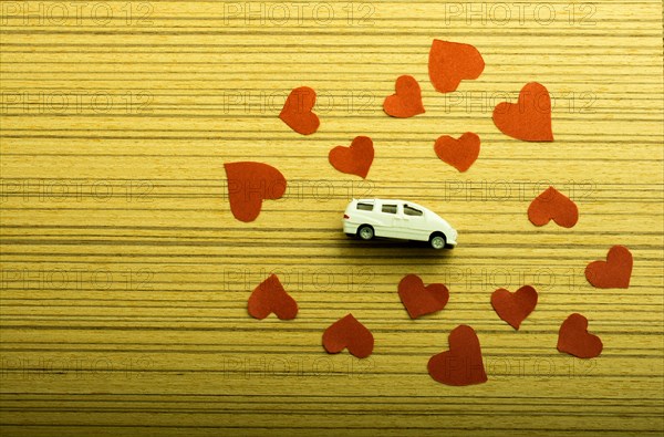 Love concept with model car and heart shaped papers