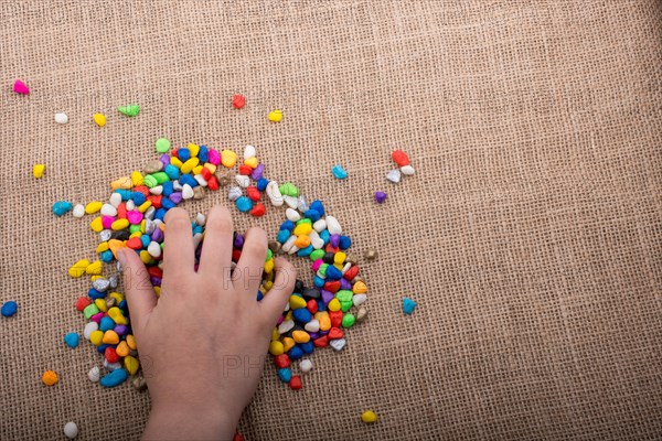 Colorful little pebbles in hand and on canvas ground