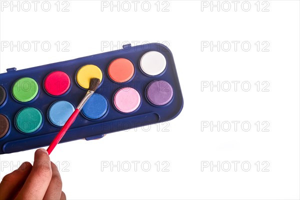 Child holding a watercolour paint set and a brush in his hand