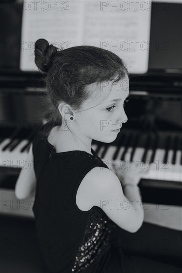 Elegant girl sits at the concert grand and plays the piano