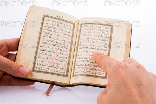 Hand holding The Holy Quran on a white background