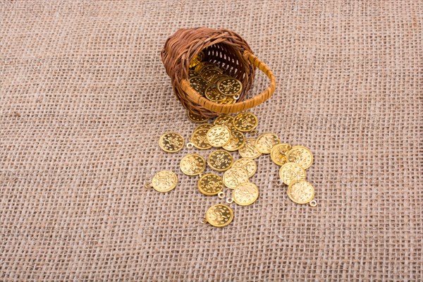 Fake gold coins out of a little basket on canvas
