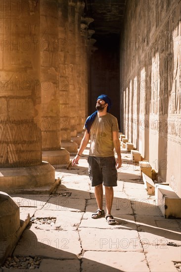 Young man in blue turban walking on the columns of the Edfu Temple near the city of Aswan. Egypt