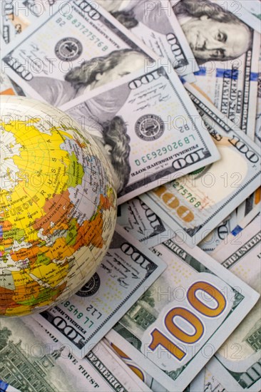 Model globe is placed on spread US dollar banknotes