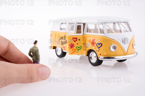 Hand holding a human figure near a peace van on a white background