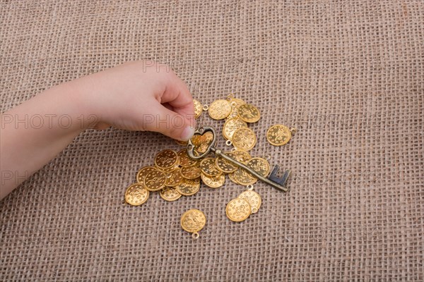 Hand holding a retro styled key over fake gold coins