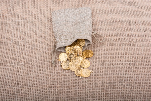 Fake gold coins out of a little sack on canvas