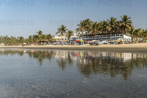 Palm trees on Kotu beach at Paradise Beach Bar and Restaurant reflected in the shallow water at low tide