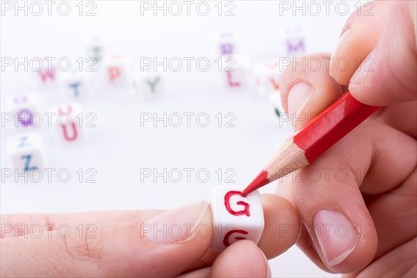 Hand holding pencil with Letter cubes on a white background