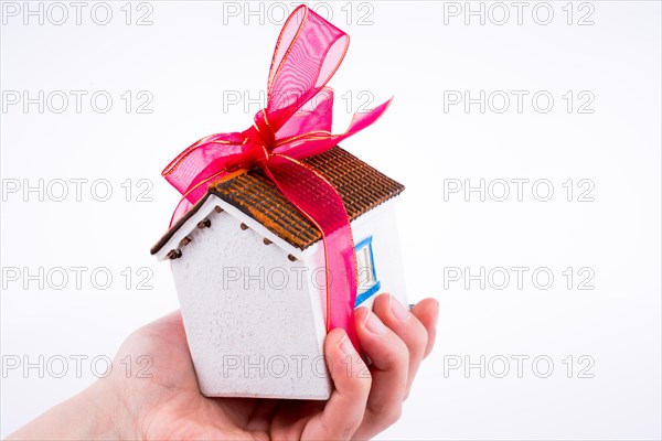 Hand holding a model house with a pink ribbon