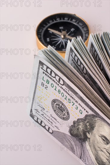 American dollar banknotes by the side of a compass on white background