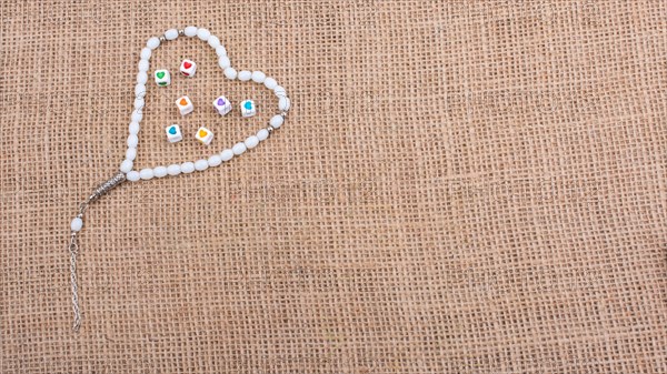 Heart shaped cubes in hand by inside a praying beads