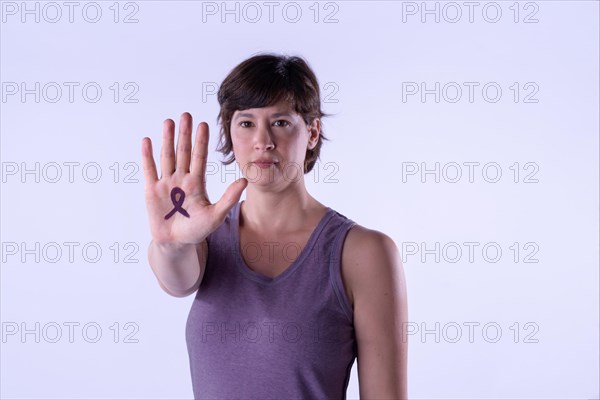 Young woman making the hand stop sign against lilac studio background