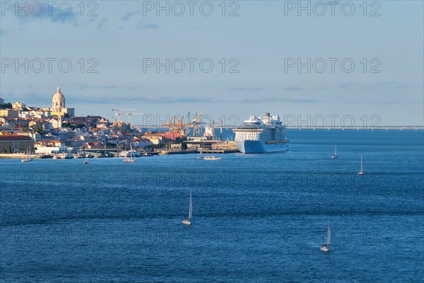 View of Lisbon over Tagus river from Almada with yachts tourist boats and moored cruise liner on sunset. Lisbon