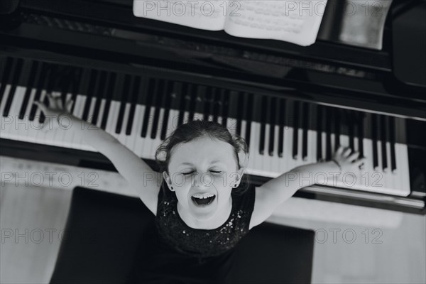 Elegant girl sits at the concert grand and plays the piano