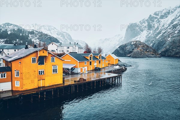 Panorama of Nusfjord authentic fishing village with yellow rorbu houses in Norwegian fjord in winter. Lofoten islands