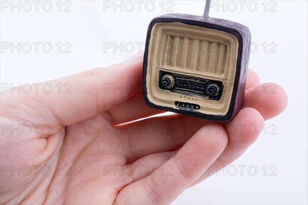 Hand holding a retro TV model on a white background