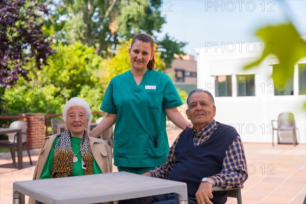 Portrait of two elderly people with the nurse in the garden of a nursing home or retirement home