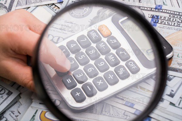 Magnifying glass is held over the banknote bundle of US dollar