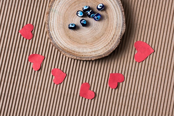 Beads on Piece of log with red paper hearts on cardboard