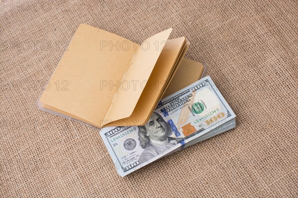 Notebook placed beside bundle of US dollar banknotes