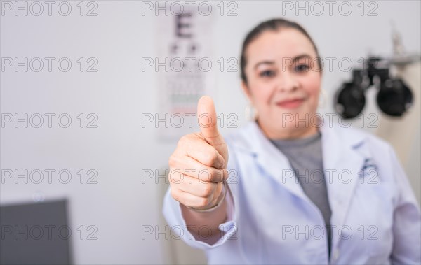Female optometrist with thumb up in the laboratory. Optometry specialist with thumb up. Smiling eye doctor with thumb up in office