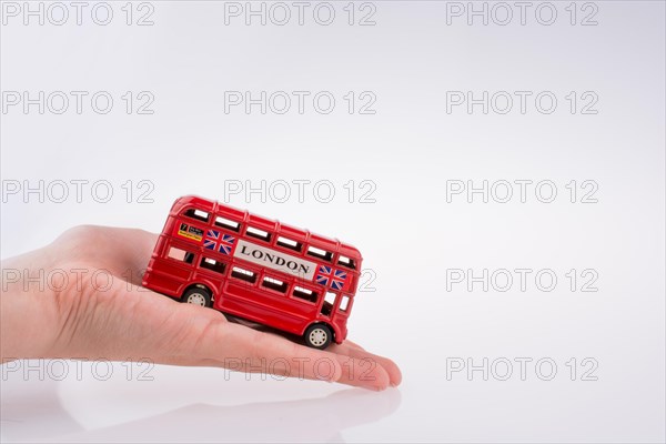 Hand holding a London double decker bus on a white background