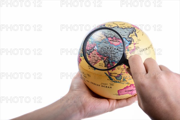 Hand holding a magnifying glass on globe in hand on white background