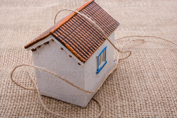 Thread wrapped around a model house on a brown background