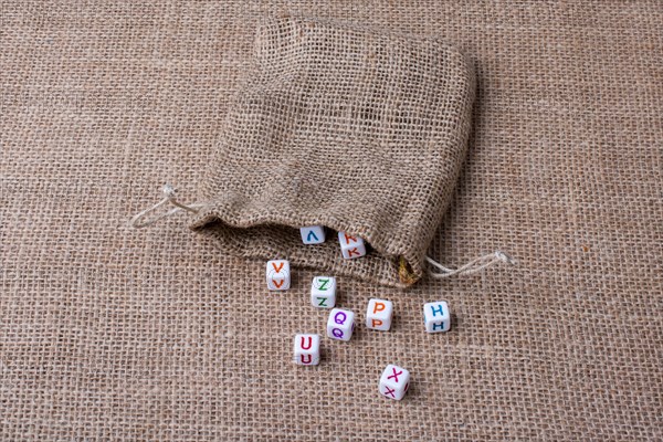 Colorful alphabet letter cubes out of sack on a canvas