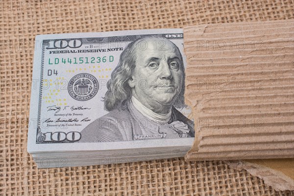Banknote bundle of US dollar partly wrapped in cardboard