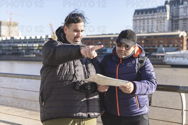Couple of friends consulting the map while exploring Puerto Madero