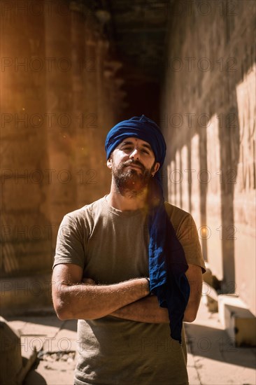 A young tourist in a blue turban visiting the Edfu Temple in the morning near Aswan city. Egypt