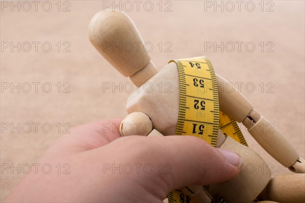 Yellow color measuring tape wrapped on wooden man