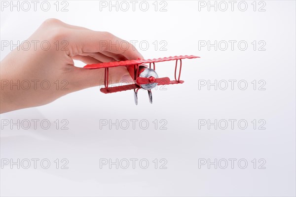 Hand holding a red toy plane on a white background