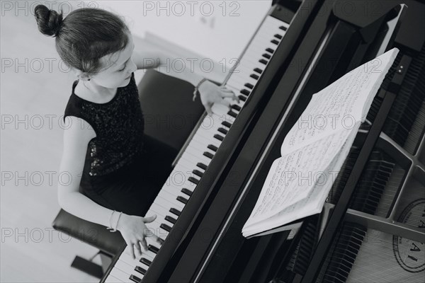 Elegant girl sits at the concert grand and plays the piano