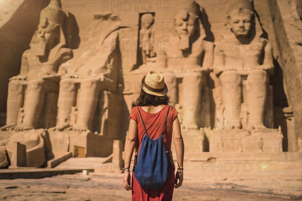 A young tourist in a red dress entering the Abu Simbel Temple in southern Egypt in Nubia next to Lake Nasser. Temple of Pharaoh Ramses II