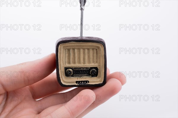 Hand holding a retro TV model on a white background