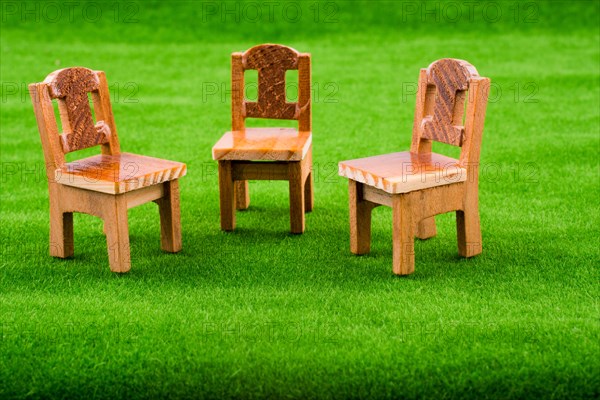 Little model wooden chairs on green fake grass
