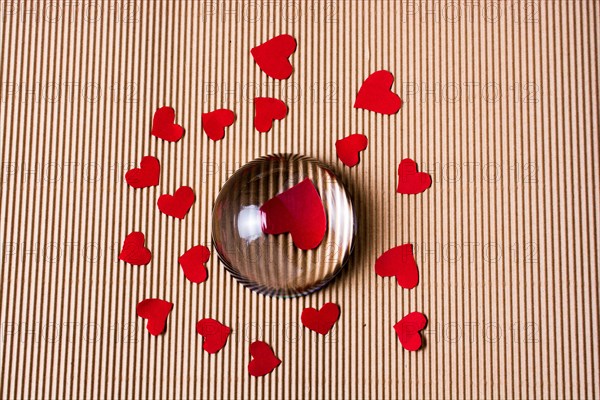 Red color paper hearts under and around half glass globe