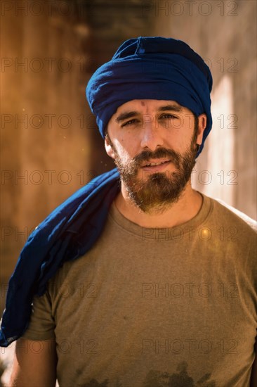 Young man in blue turban walking on the columns of the Edfu Temple near the city of Aswan. Egypt