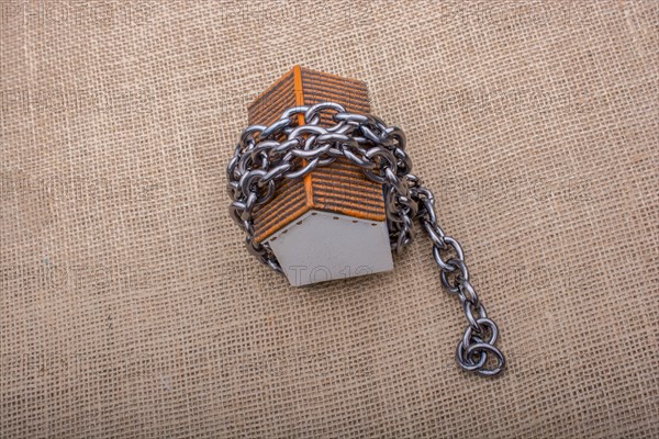 Chain wrapped around a model house on a brown background