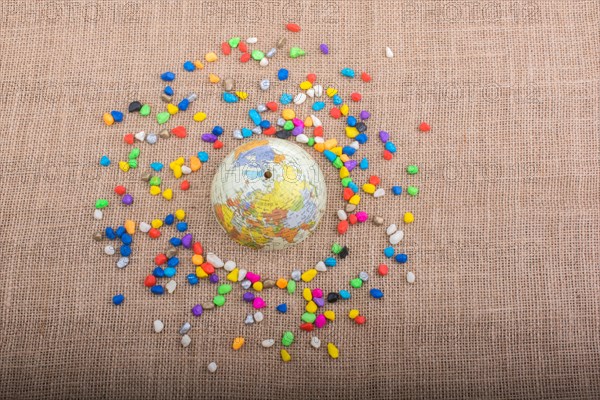 Model globe placed amid colorful pebbles