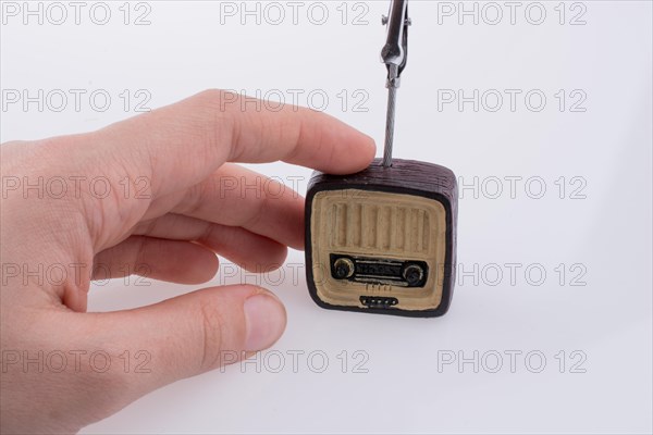 Hand holding a retro TV model on a white background