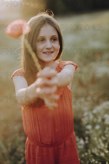 Girl in a red dress in a poppy meadow