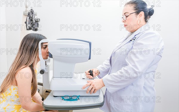 Optometrist checking the eyesight of a patient with an autorefractor. Oculist doing eye exam to female patient