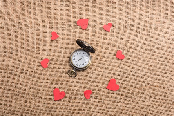Love concept with pocket watch and paper hearts on threads