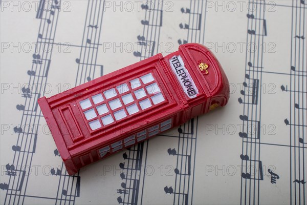 Telephone booth is placed on paper with musical notes